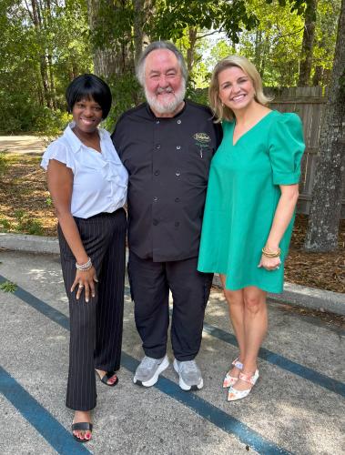 Chef Pat Gallagher stands between podcast hosts Zondra and Katie outside the Northshore Media Group studios.