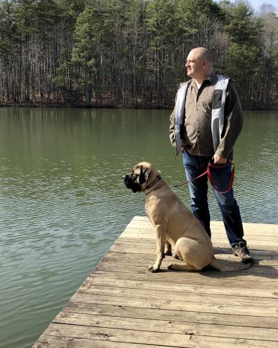 A dog and man standing on a wooden dock on a nature trail