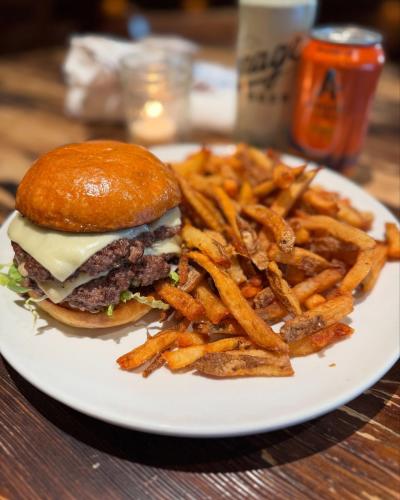 a burger and fries on a plate with beer in the background