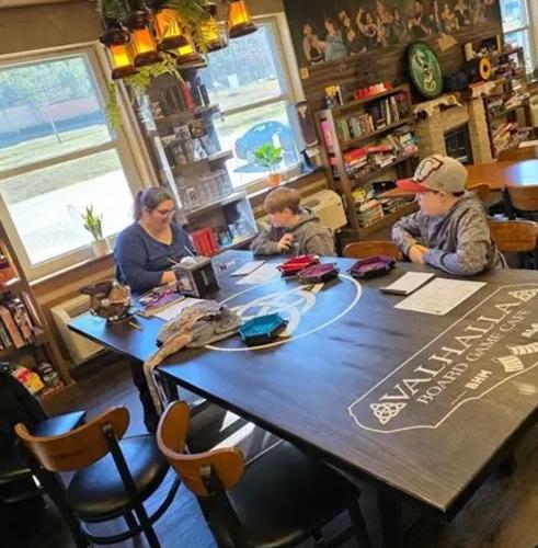 A family of three (one mother and two sons) sit around a table playing a game of Dungeons and Dragons.