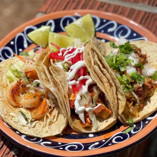 Three tacos from El Barrio sit on a plate.
