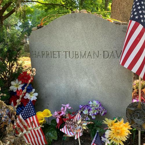 Harriet Tubman's grave marker with flowers and flags