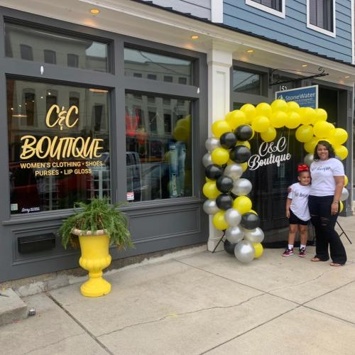 A woman and child under a balloon arch outside the New Albany C&C Boutique.