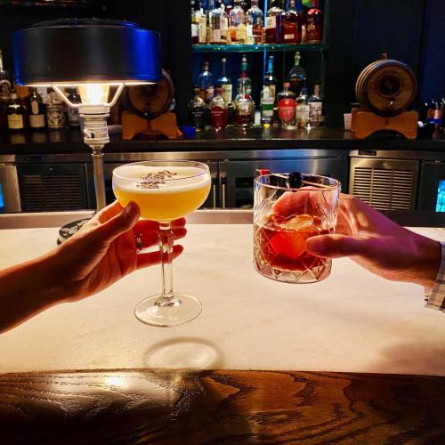 A couple raising their cocktail glass at The Keep inside Hotel Leveque