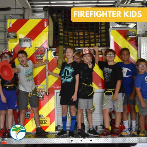 Kids stand on the back of a firetruck during Firefighter Camp in Palm Coast.
