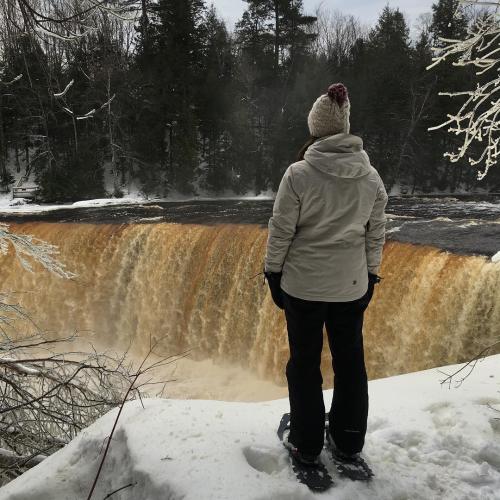 A person with snowshoes on overlooks Tahquamenon Falls in the winter, located in Michigan's Upper Peninsula, USA