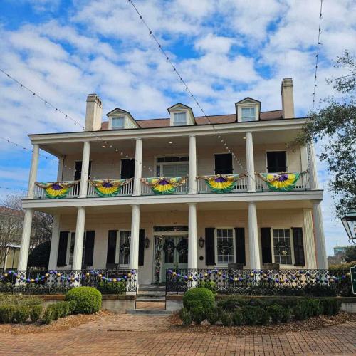 Two story white house with columns and Mardi Gras decorations