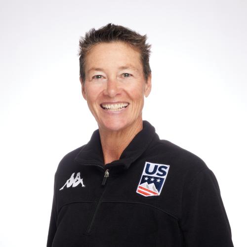 Smiling woman with short hair wearing a black zip up that has US Ski and another black and white logo on it