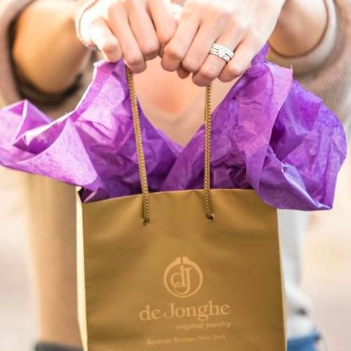 woman holding gift bag with purple tissue paper