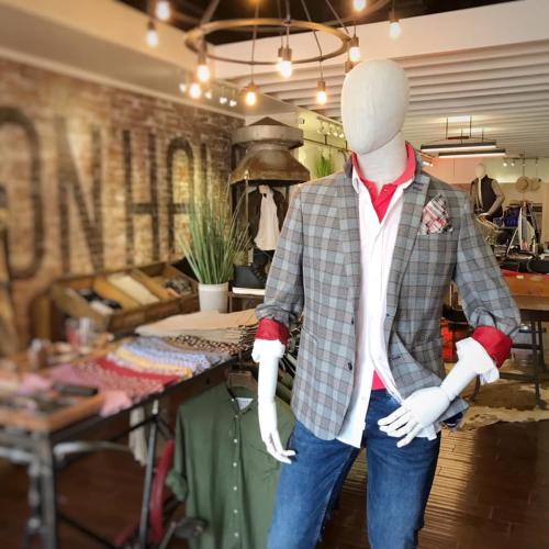 Male mannequin dressed in jeans and layered tops with exposed brick wall in the background
