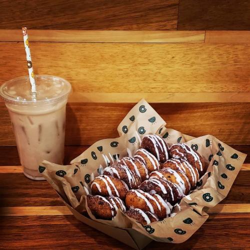 Basket of donut holes drizzled with icing and an iced coffee