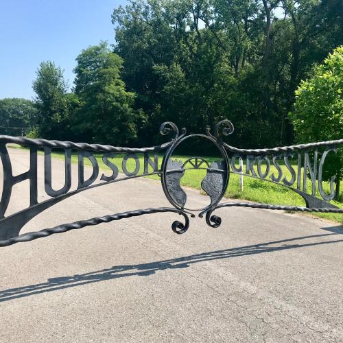 gate that says Hudson Crossing on a sunny day