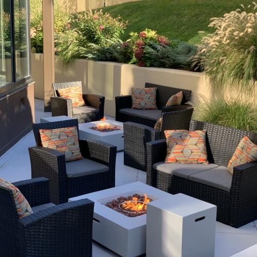 The outdoor firepit area at the Sonesta White Plains Downtown. Couches and plush seats surround the firepits.