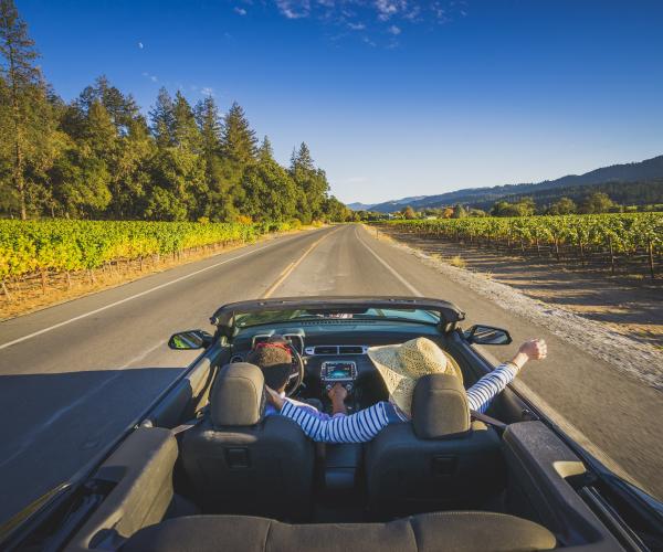 Visitors enjoy the sunshine and fresh air in their convertible on a drive through Napa Valley