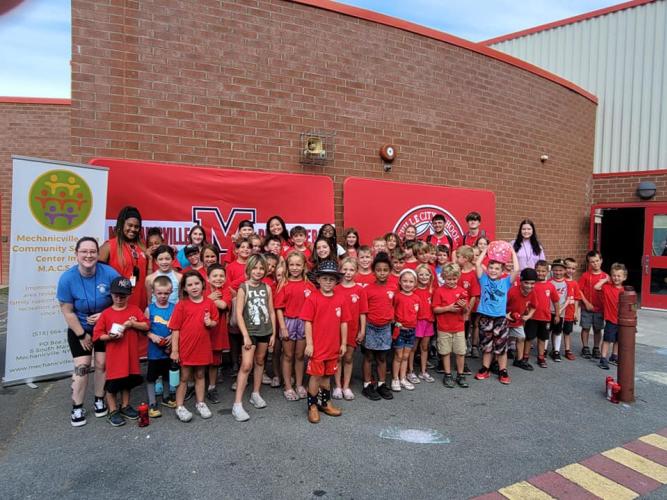 Large group wearing red shirts posing in front of community center