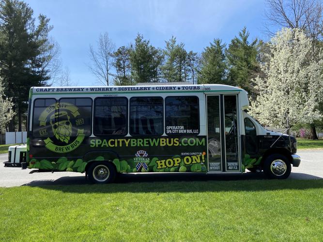 Brew Bus with logos on side parked in front of blossoming tree