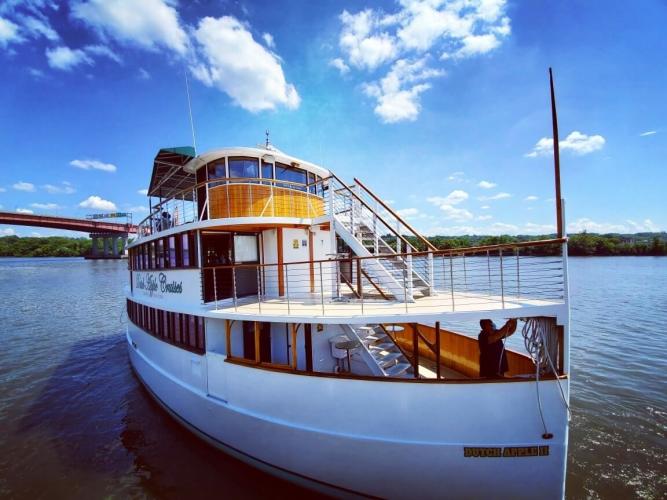 Large white boat on river with puffy white clouds