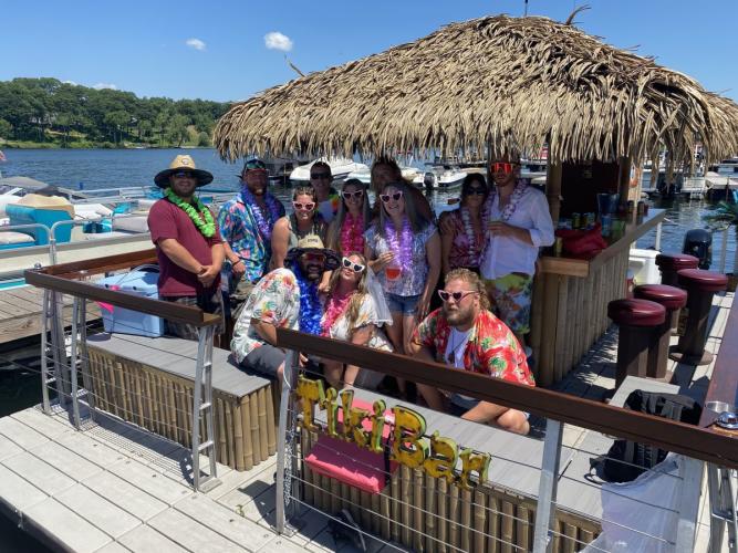 Group of people posing under thatched roof of tiki boat