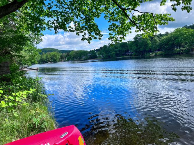 View of very blue lake with tip of red kayak in lower corner