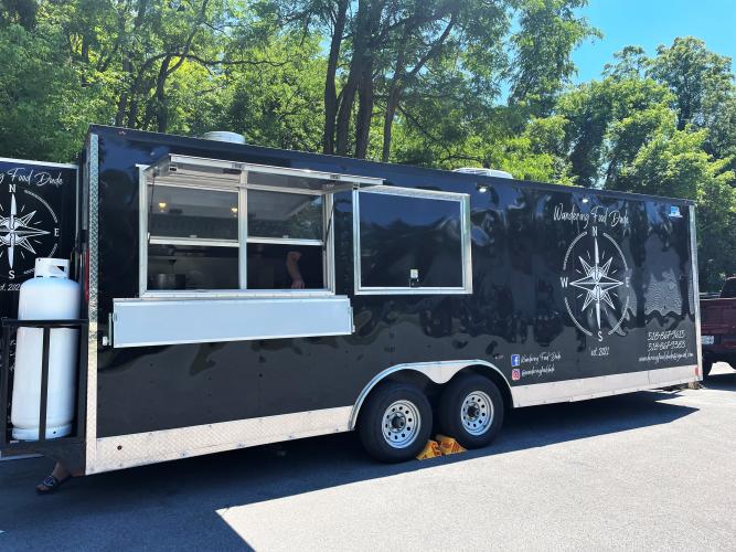 Large black food truck with Wandering Food Dude logo