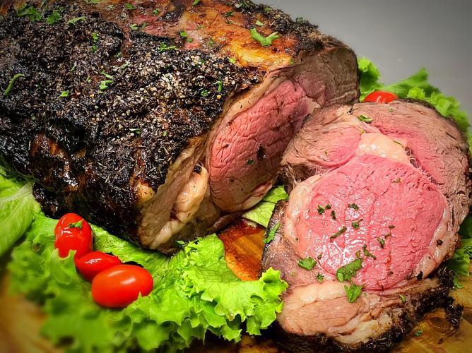 Closeup of prime rib on cutting board with lettuce leaves on the side