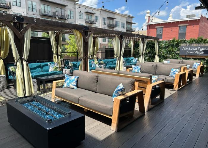Rooftop patio at Stella’s Elixir Lounge featuring cabana seating, outdoor sofas, string lights and a fire table.