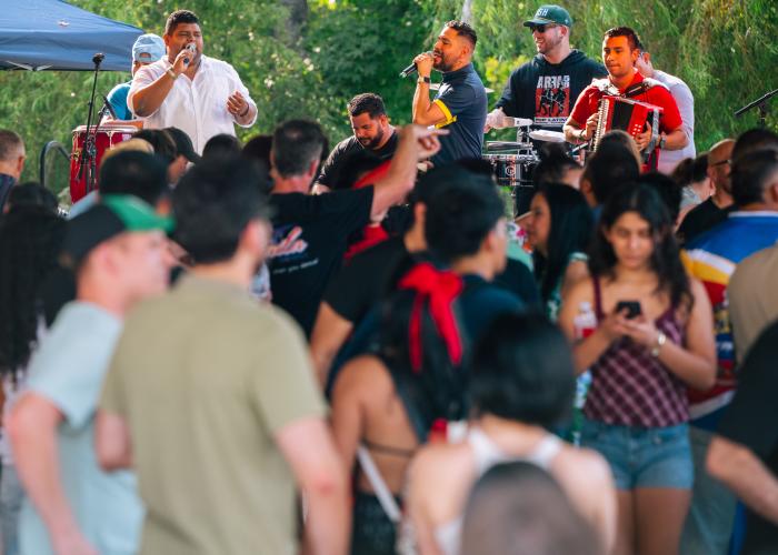 Live band performs for a crowd during the CulturA Festival at The Orion Amphitheater in Huntsville, featuring vocalists, percussion, and accordion.