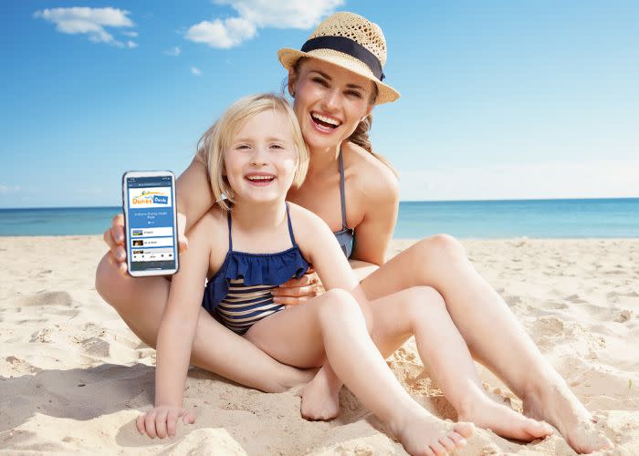Woman holding a cellphone with kid in her lap on a beach