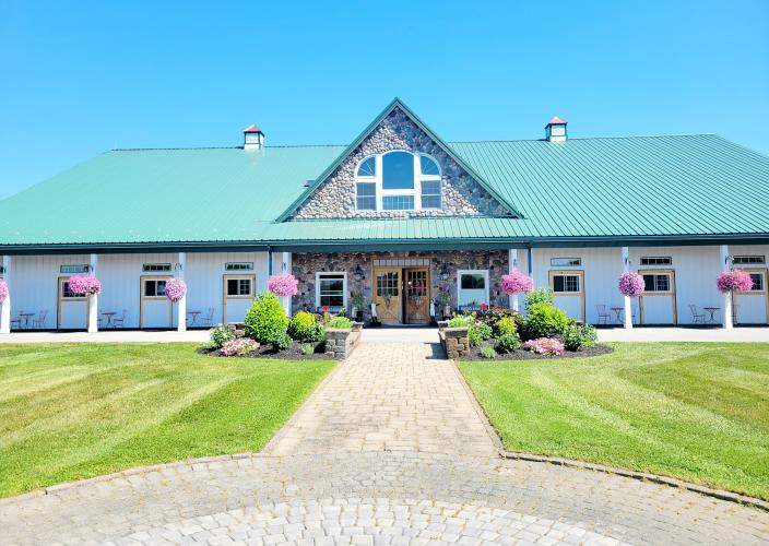 Exterior photo of spa with blue sky and multiple pink hanging baskets of flowers