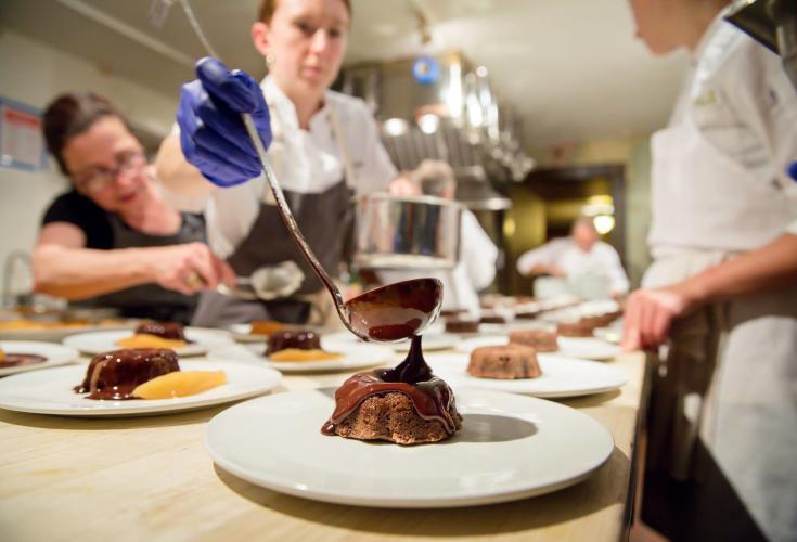 Chef putting chocolate topping on lava cake