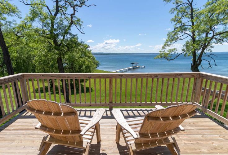Two Adirondack chairs on deck of vacation rental overlooking lake