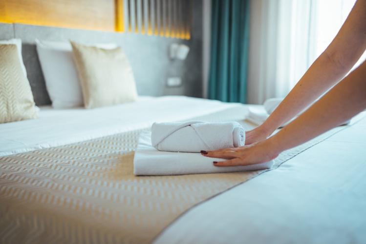 Woman's hands placing folded towels on hotel bed