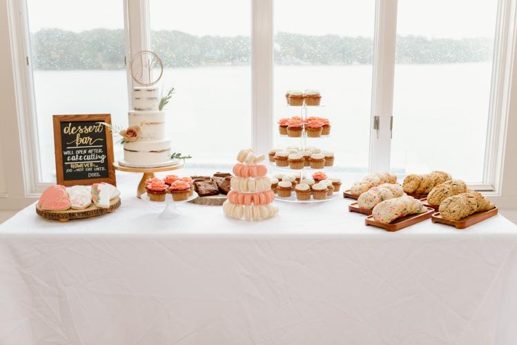 Dessert table with pink and white treats overlooking a lake