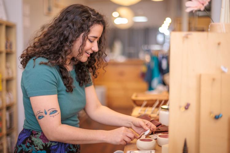 woman looks a jewelry in Community shop in downtown Athens.