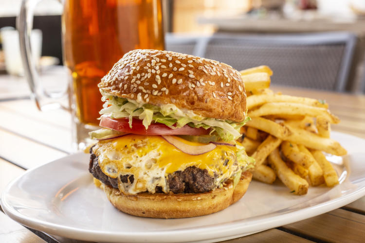 A cheeseburger with egg located on a plate with french fries