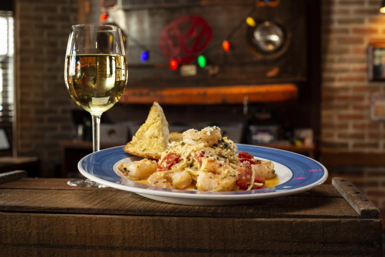 A plate of shrimp scampi and a glass of white wine from Rusty Bucket Tavern
