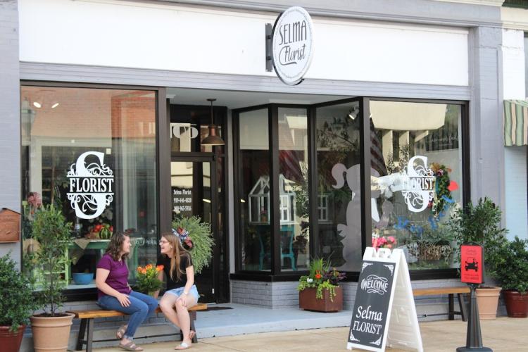 Exterior of Florist Store with two girls chatting on a bench