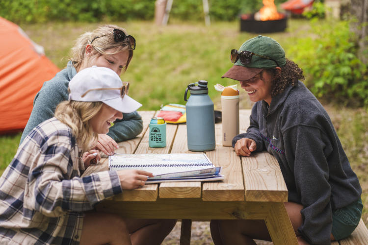 A group of friends sitting around a picnic table at a campsite in Marquette, Michigan.