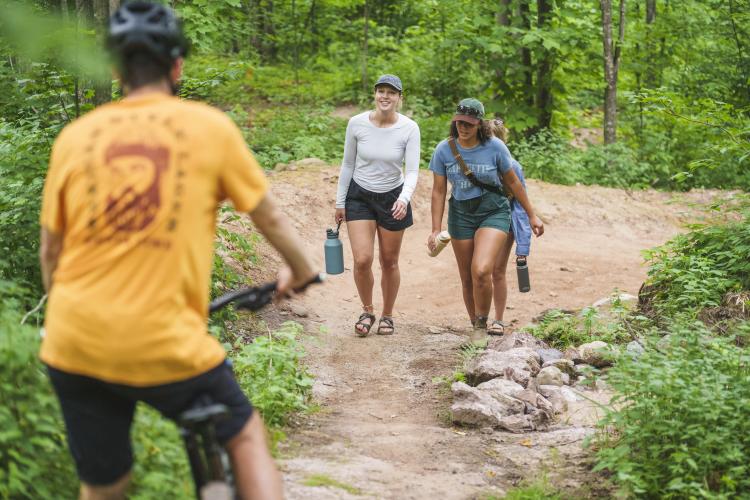 A biker yielding to uphill hikers on a trail in Marquette