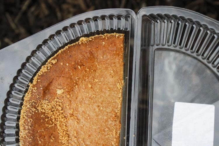 Half of a peanut butter pie with a crumb topping inside a clear plastic takeout container.