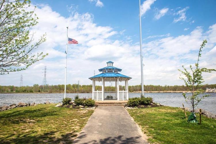 A path leads up to a gazebo with an American flag flying next to the gazebo. The gazebo looks out onto the lake.