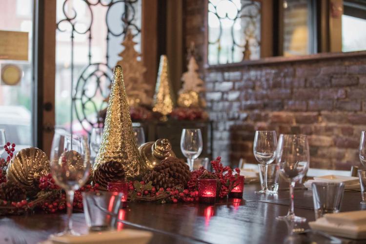 Boca dining table decorated with gold holiday trees, pine cones and tiny white lights