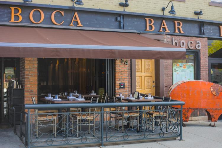 Empty tables and chairs at Boca Bistro's patio with orange metal pig