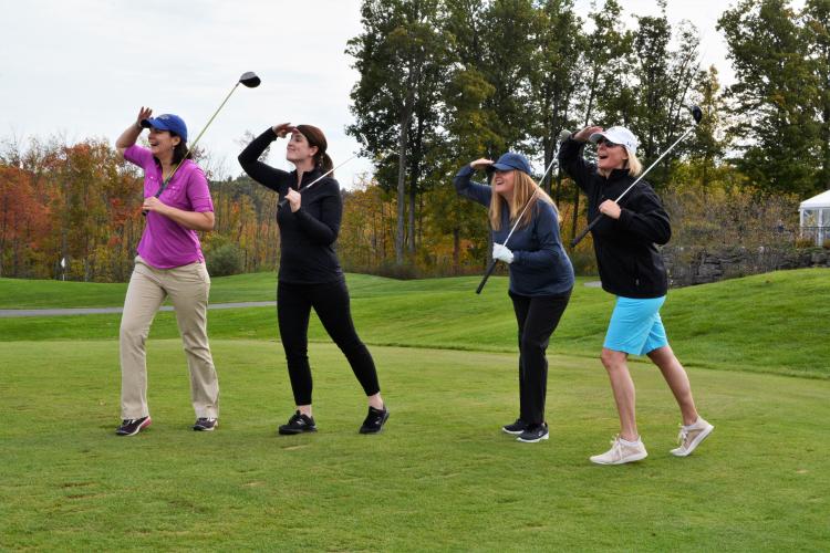 Amy Smith and 3 others posing on the green with their hands up shading their eyes as they look off in the distance for their balls