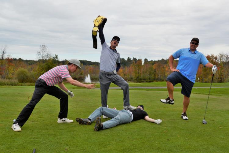 Carmine DeCrescent and 3 others posing over a body laying on the green holding warrior belt in victory