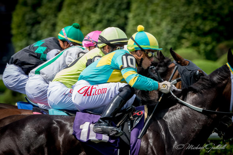 Four jockeys side by side in a race