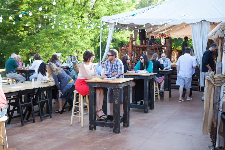 People enjoying the outdoor patio at Saratoga Winery with string lights and some shade