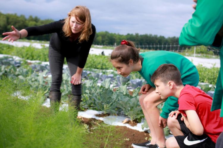 Teacher instructing two children in farm fields