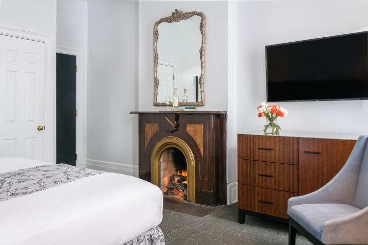 Guest room showing corner of bed, fireplace and TV on wall