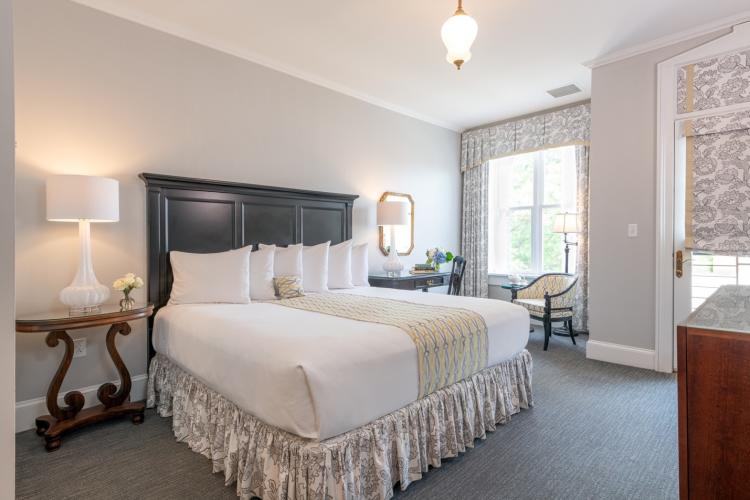 Guest room with large bed, all in white and light print